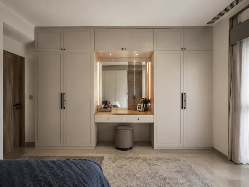 Wardrobe with dressing desk: A dressing recess breaks a long storage wall and gives smaller everyday items their own drawers and lit mirror.
